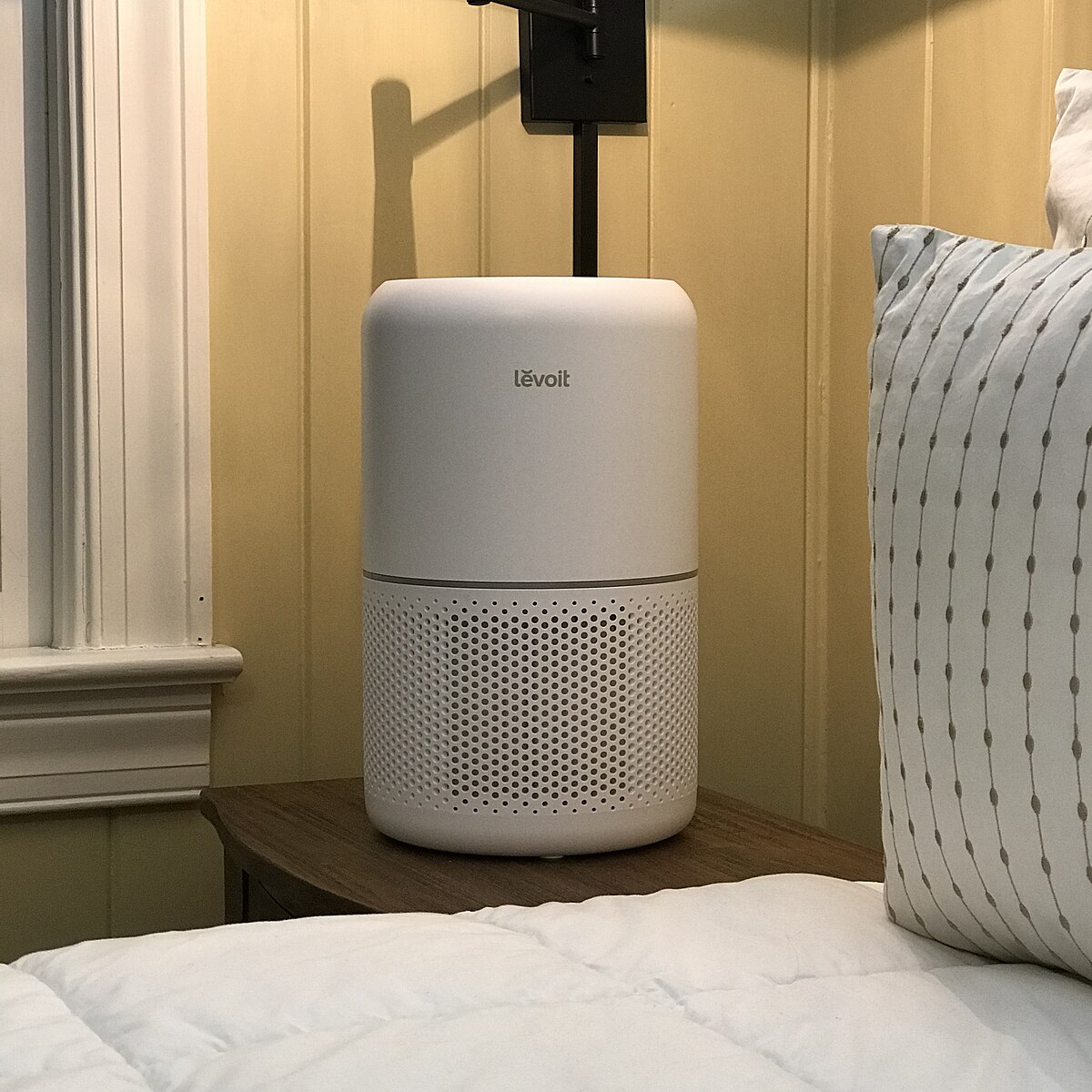 A Levoit Core 300-P air purifier on a nightstand next to a bed.

“Air Purifier (Levoit Core 300) (49318249796)” by Home Air Quality Guides is licensed under CC BY-SA 2.0.