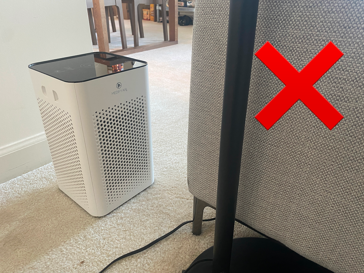 A Medify MA-25 air purifier hidden behind a couch.