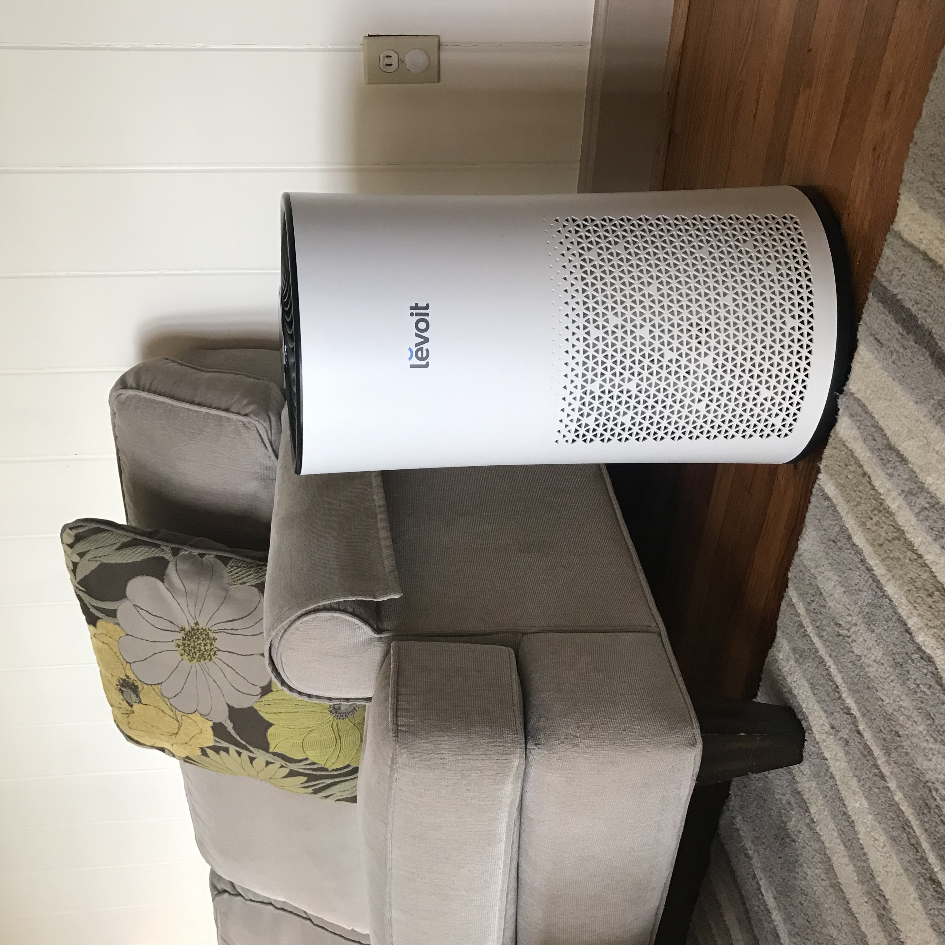 Image of an air purifier sitting next to a couch in a living room 